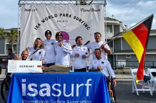 Deutsches Para Surf Team bei der WM 2021 vor dem Logo des ISA Worlds