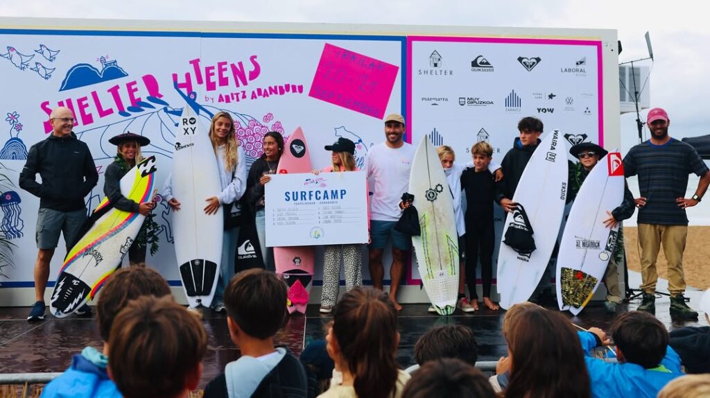 Surfers celebrating after a comp on a podium holdig up their boards